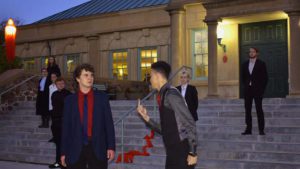 Students perform a play outdoors at night on the library steps