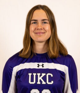 Margot's team photo. She is wearing a UKC team shirt and has shoulder length brown hair