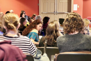 close up shot of audience listening and taking notes at writing conference