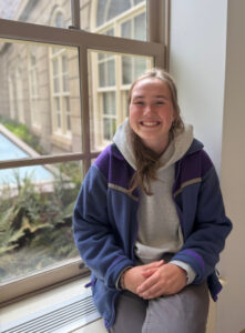 Sarah sits on a window sill looking out to Willwerth Garden.