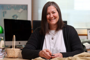 Dr. Lisa Binkley sitting at desk - She will be speaking at the lecture series exploring exploitation & marginalization of Indigenous and Black communities.