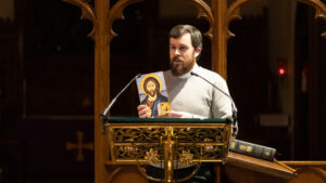 former chapel administrator, Ben von Bredow standing at lectern holding icon - wider shot