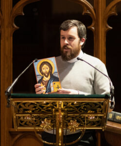 former chapel administrator, Ben von Bredow standing at lectern holding icon
