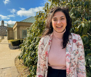 Emma Naguib standing in front of rhododendron bush and King's library in background.