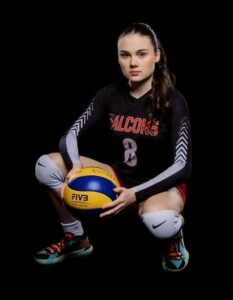 Photo of Blagdon wearing her falcons shirt, crouching down and holding a volleyball. shot with black background