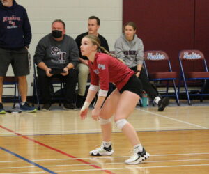 Photo of Foulkes on volleyball court crouched and ready to receive ball