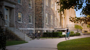 Student riding bike past Arts & Administration building on King's campus.