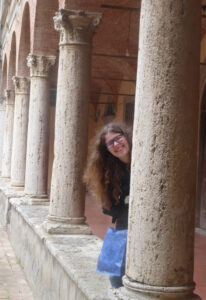 Pic of Susanna Cupido leaning out from behind a column in an ancient building.