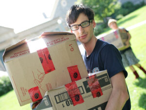 young man holding cardboard boxes on moving in day