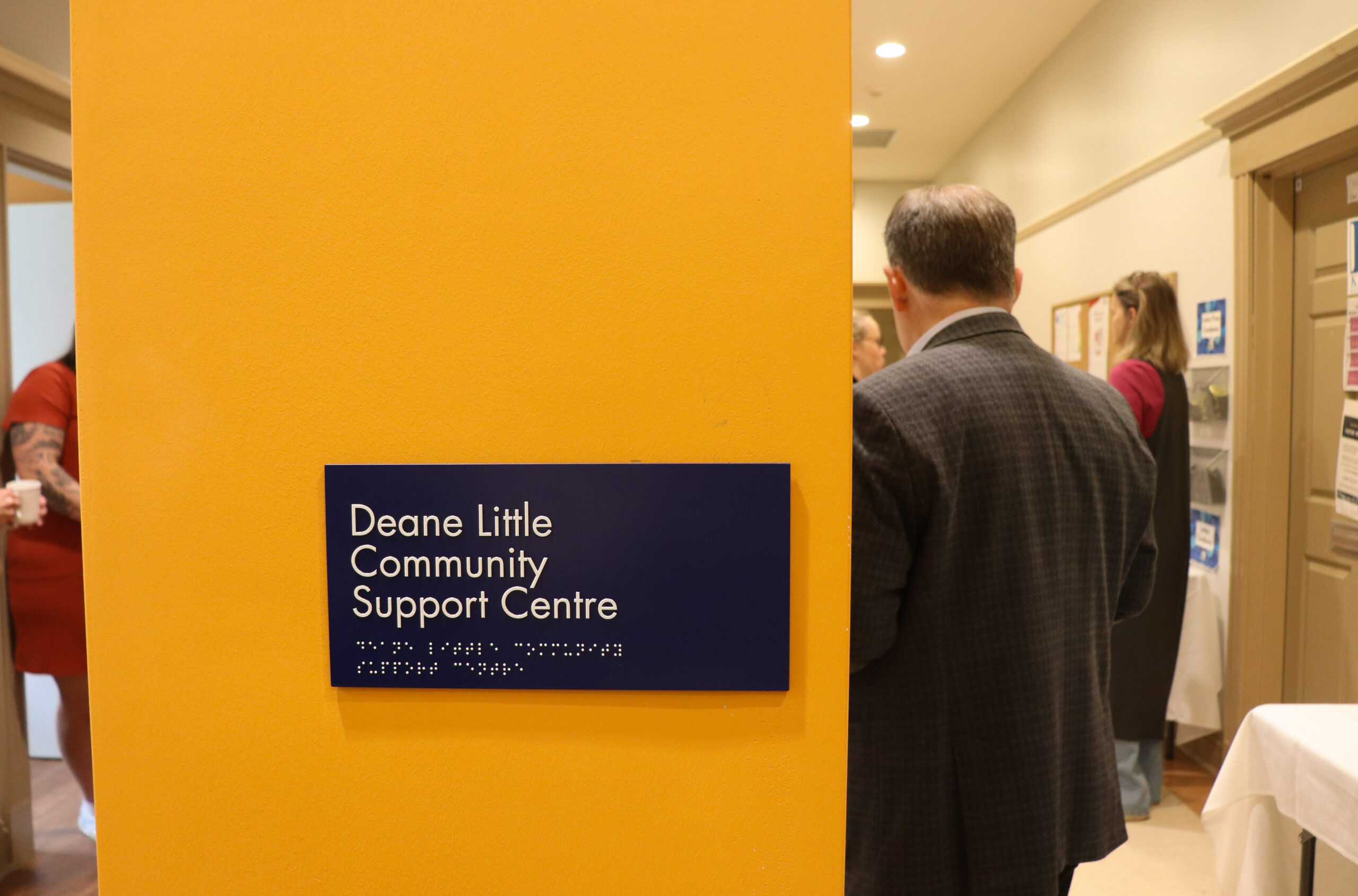 A sign on an orange wall reading "Deane Little Community Support Centre."