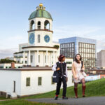 2 students walk up Citadel Hill late afternoon with Halifax's clock tower in background