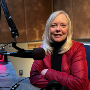 Pauline sits in audio studio with microphone in front of her.