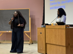 Professors Eternity Martis and Nana aba Duncan stand in front of Alumni Hall presenting their research to journalism students