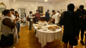 a gathering stands around the dining room table in the Lodge for the Black Student Mixer.