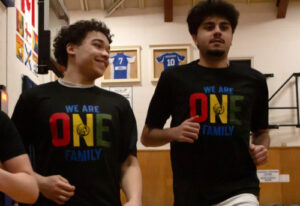 Two King's basketball players wear warm up shirts featuring African Heritage Month logos