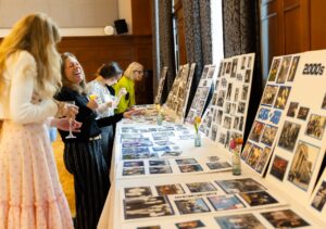 alumni laughing over old pictures on display boards in Prince Hall