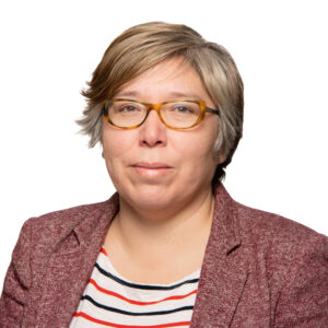 Ann wears a red woolen blazer over an off white orange and black striped shirt - the background is white