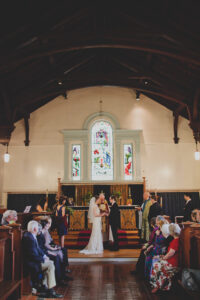 bride and groom stand facing each other at altar as they marry in chapel