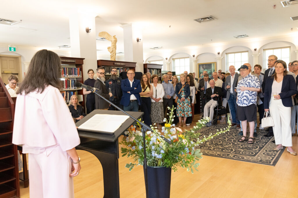 wide shot behind Chancellor Deane Little of the crowd gathered in the Library for Pres. Lahey's farewell.