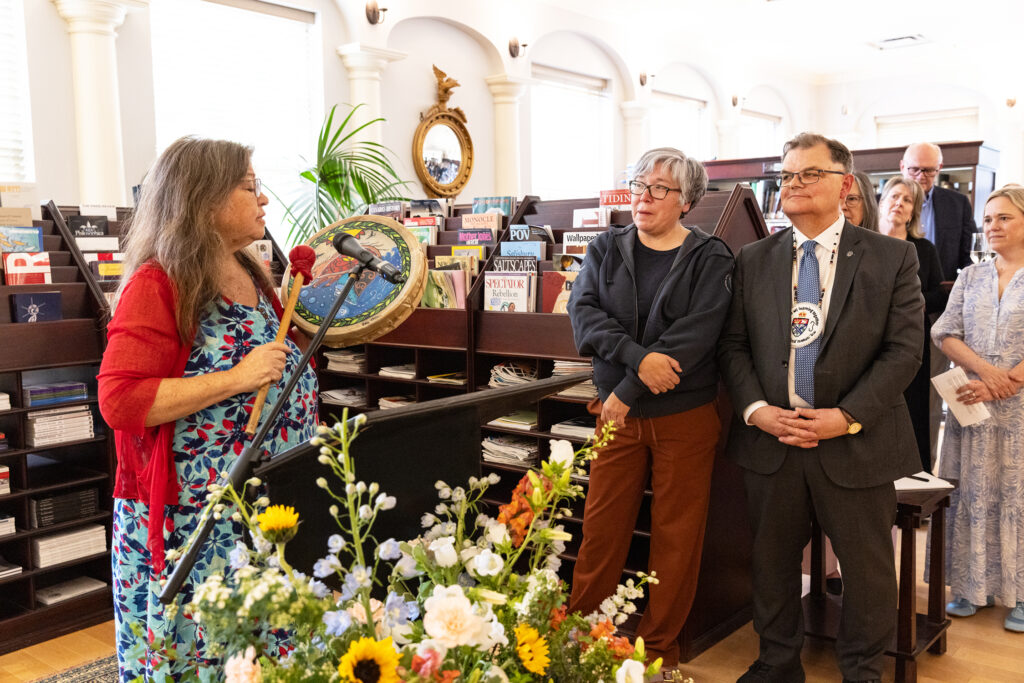 Board Member Catherine Martin plays a Mi'kmaw drum and sings while Dr. Ann Sylliboy and President Lahey stand to the right.