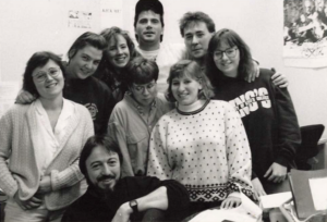 group of students gather for photo in newsroom with stephen kimber crouching in front. photo is in black and white